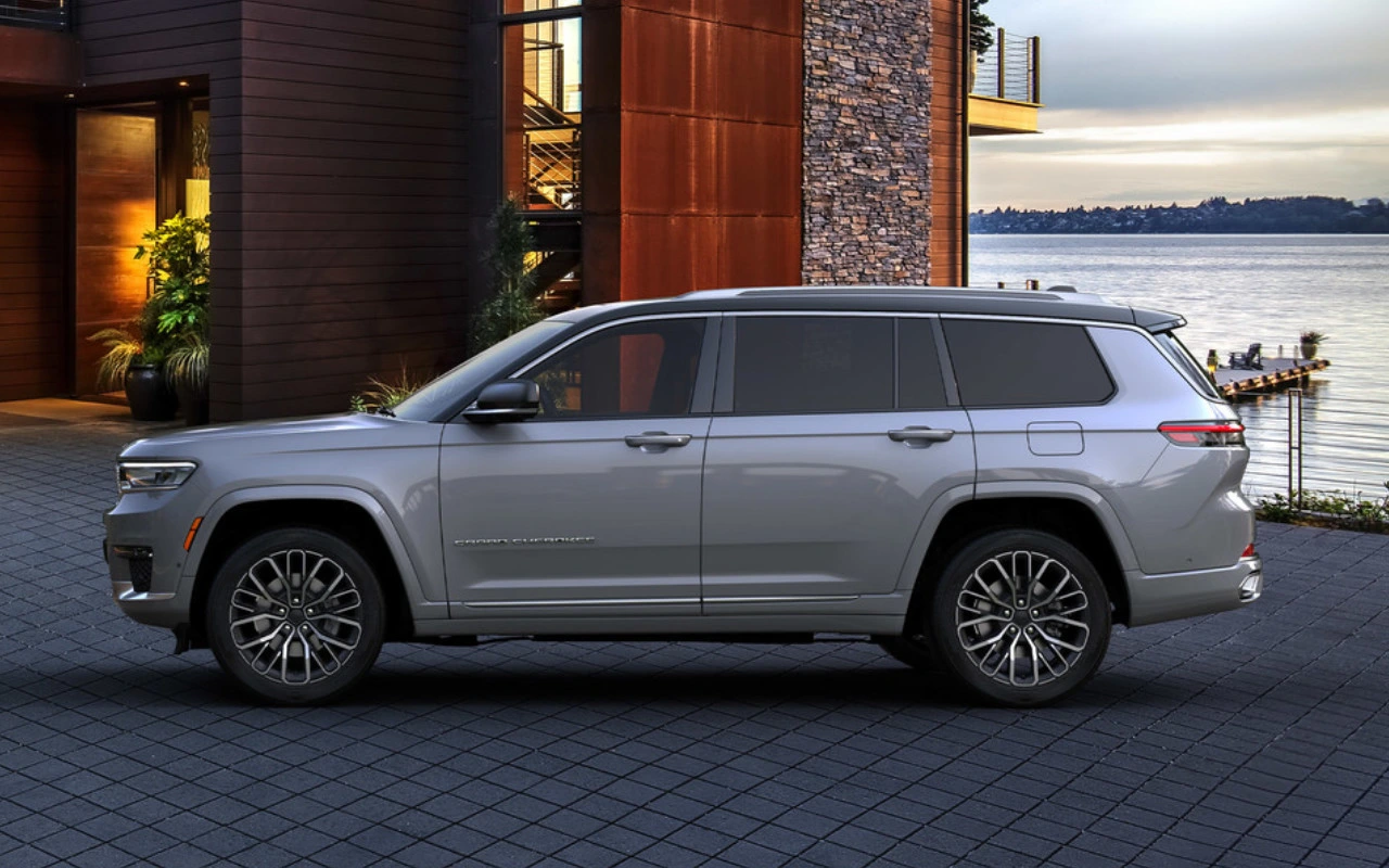 vue latérale d'un Jeep Grand Cherokee 2023 devant une maison sur le bord d'un lac