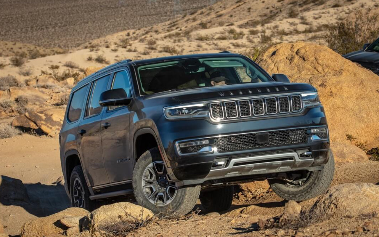 vue latérale avant d'un Wagoneer 2023 sur un chemin rocailleux dans le désert