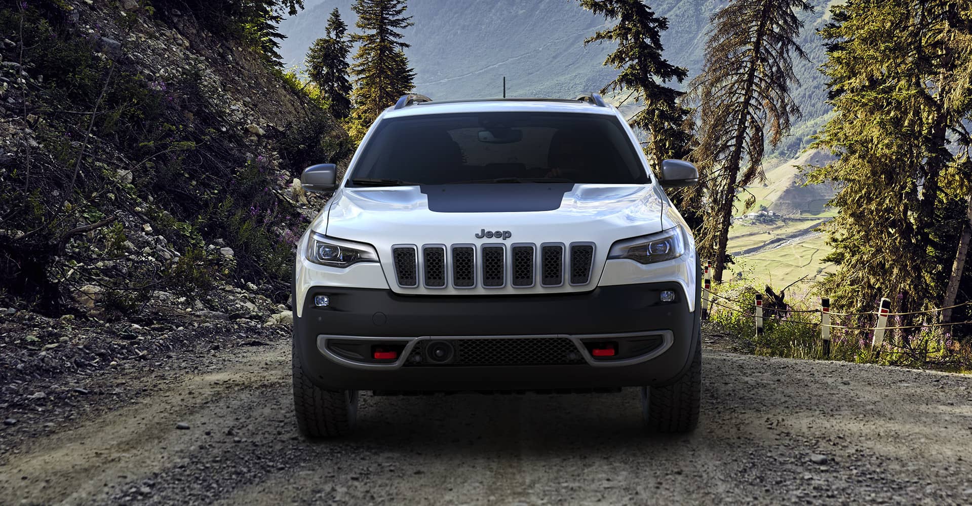 vue avant du Jeep Cherokee Trailhawk 2021 blanc garé sur un chemin de terre dans la nature